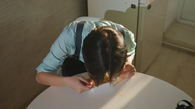Asian man eating noodles at table, young asian diner sampling takeout with chopsticks and close focus on food scattered grains and sunlight create candid kitchen atmosphere, playful reaction builds