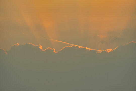 Golden sun rays breaking through thick clouds at sunset dramatic sky background