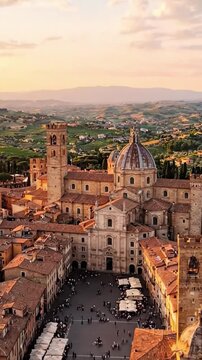 Breathtaking Aerial View of Historic Town Square Surrounded by Majestic Architecture and Lush Green Hills at Sunset