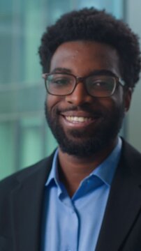 Serious African American business man look away turning looking at camera happy smiling in office. Ethnic confident businessman smile toothy male executive worker specialist startup ceo posing indoors