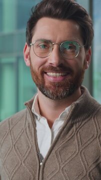 Thoughtful Caucasian business man in glasses looking at camera smiling cheerful successful businessman male executive smile joyful at office. Pensive adult entrepreneur agent look happy in company