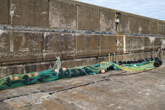 Fishing net spread along the concrete harbour wall at Buckie Harbour in Moray Scotland during the daylight hours for maintenance and storage