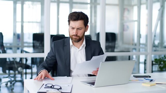Focused Caucasian mature business man managing corporate papers busy with company paperwork management middle-aged businessman male executive inspecting documentation correspondence letters in office