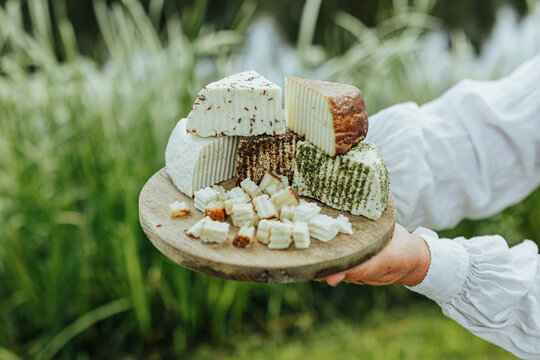 Assorted fresh goat cheeses served on a rustic wooden board outdoors, highlighting artisanal food, local production, eco tourism and authentic rural gastronomy