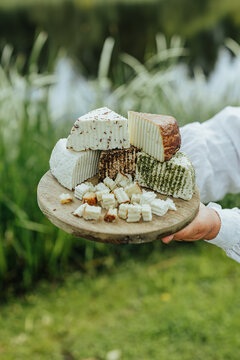 Assorted fresh goat cheeses served on a rustic wooden board outdoors, highlighting artisanal food, local production, eco tourism and authentic rural gastronomy