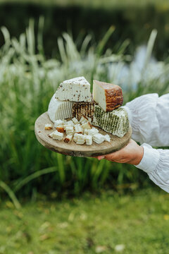 Assorted fresh goat cheeses served on a rustic wooden board outdoors, highlighting artisanal food, local production, eco tourism and authentic rural gastronomy