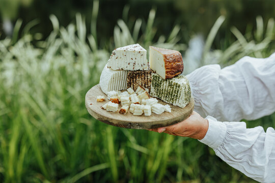 Assorted fresh goat cheeses served on a rustic wooden board outdoors, highlighting artisanal food, local production, eco tourism and authentic rural gastronomy