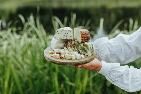 Assorted fresh goat cheeses served on a rustic wooden board outdoors, highlighting artisanal food, local production, eco tourism and authentic rural gastronomy