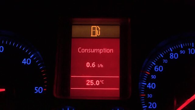 Low fuel warning light glowing on a digital car dashboard. Digital instrument cluster screen in vehicle showing fuel reserve indicator and outside temperature.