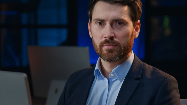 Headshot portrait Caucasian middle-aged business man working computer looking at camera at night dark late office businessman male professional work online posing serious in evening corporate agency