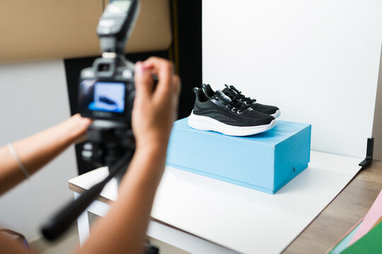 Product photographer taking professional e-commerce pictures of black athletic shoes in a minimalist studio setup