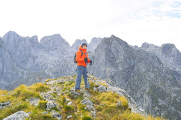 Fototapeta premium Traveler stands on rocky karst ridge, dramatic limestone peaks of Prokletije massif in background. Conveys alpine route exposure, off-the-beaten-path wilderness experience, and mountain exploration.