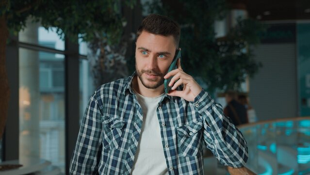 Positive happy Caucasian business man talking mobile phone call client buyer smiling carefree in shopping mall company male guy businessman talk smartphone smile joyful chatting online discuss indoors