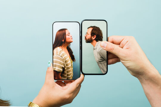 People kissing through smartphone screens maintaining long distance relationship with virtual intimacy and online communication