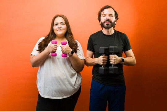Healthy adult couple training with dumbbells for wellness and body positivity representing different fitness levels