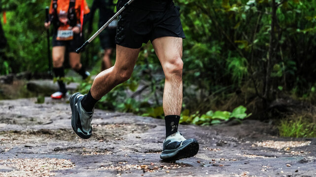 Trail runner navigating a rocky forest path during an outdoor endurance race