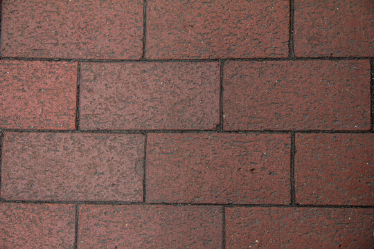 Texture of red brick pavement seen in a city street during the day