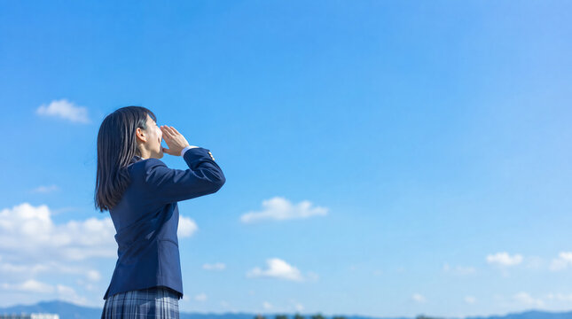 青空の下、遠くに向かって叫ぶ高校生女子　青春の情熱、エール