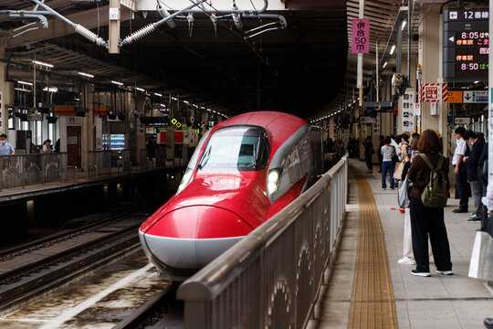 Modern Red Shinkansen Bullet Train Arriving at a Japanese Railway Station Platform