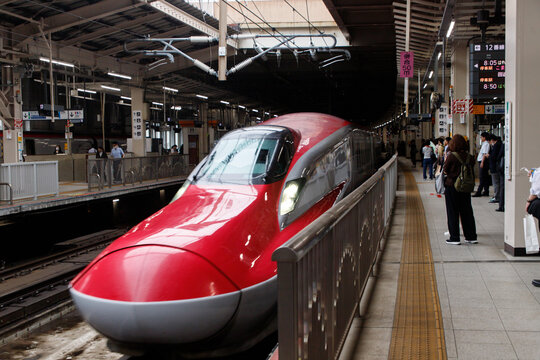 Modern Red Shinkansen Bullet Train Arriving at a Japanese Railway Station Platform