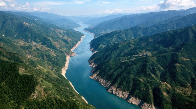 A majestic river carving its way through a deep valley, flanked by lush, verdant mountains. The panoramic view captures the grandeur of nature and the serene flow of water.