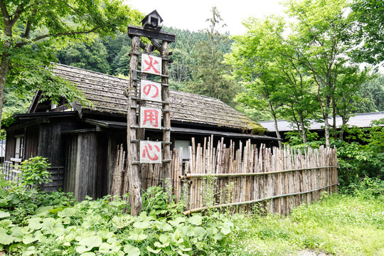 Traditional Japanese Wooden Building with Bamboo Fence and Fire Prevention Sign in a Lush Forest