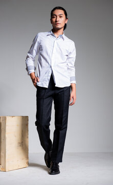 Asian sexy man wearing a white shirt and suit pants against a gray background