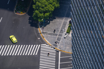 High angle view of a paved forecourt and zebra crossing beside a corporate tower, the corner radius traced in bright yellow kerb paint, junction performance in a dense core. © ultramansk