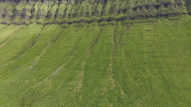 Detailed aerial drone footage of the rocky cliff face and eroded green slopes of Benbulben, County Sligo, Ireland.
