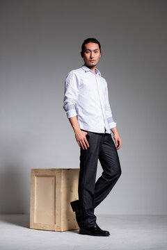 Asian sexy man wearing a white shirt and suit pants against a gray background