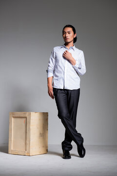 Asian sexy man wearing a white shirt and suit pants against a gray background