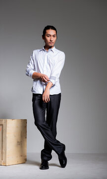 Asian sexy man wearing a white shirt and suit pants against a gray background