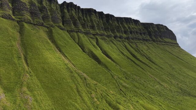Angled aerial perspective of the rugged green slopes and rocky ridges of Benbulben mountain, County Sligo, Ireland.