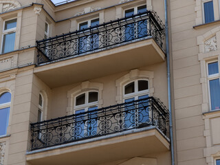 An ornate iron balcony railing on a beige residential building facade, highlighting classical...