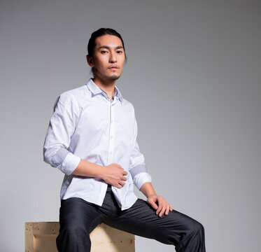 Asian sexy man wearing a white shirt and suit pants against a gray background