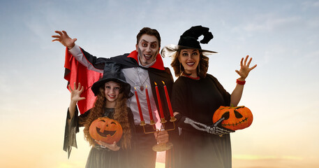 Obraz premium Happy Family Dressed in Halloween Costumes Outdoors at Sunset