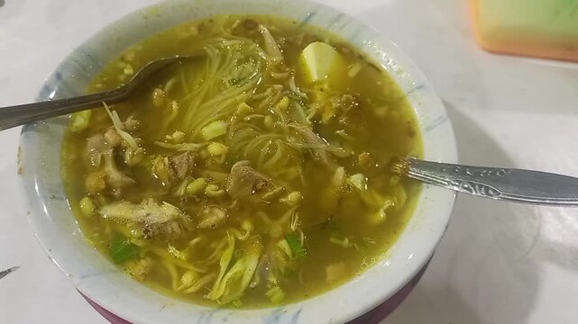 Hot bowl of traditional indonesian soto ayam soup with noodles