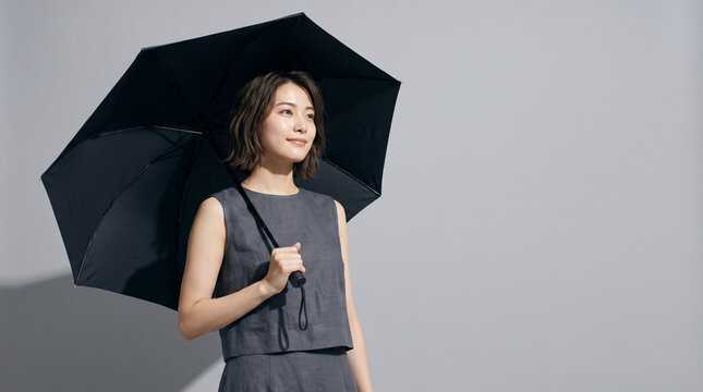 黒い日傘をさして立つ女性 紫外線対策や日焼け予防のイメージ コピースペース
