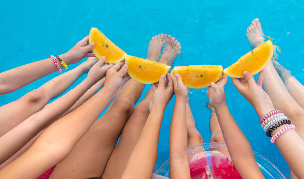 Children eating watermelon by the pool. Selective focus.