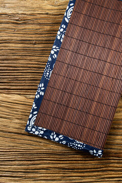 Decorative table mat made of bamboo and fabric on a wooden surface