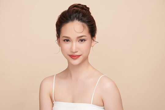 A beautiful young Asian woman with clean, fresh skin against a beige background. Skincare, facial treatment, cosmetology, beauty, and spa. An elegant portrait of an Asian woman.