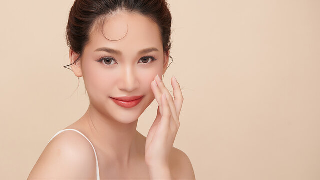 A beautiful young Asian woman with clean, fresh skin against a beige background. Skincare, facial treatment, cosmetology, beauty, and spa. An elegant portrait of an Asian woman.