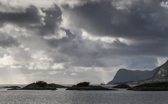Dramatic lighting, dark clouds, islands and archipelago off the coast near &Aring;lesund or Alesund, M&oslash;re og Romsdal Fylke, Norway