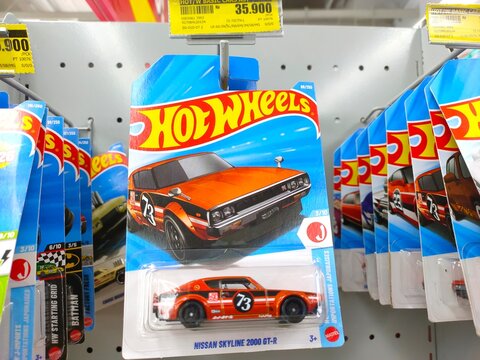 Malang, Indonesia - July 18, 2026: An orange Hot Wheels "Nissan Skyline 2000 GT-R" die-cast toy car in its original blister card packaging hanging on a store rack.