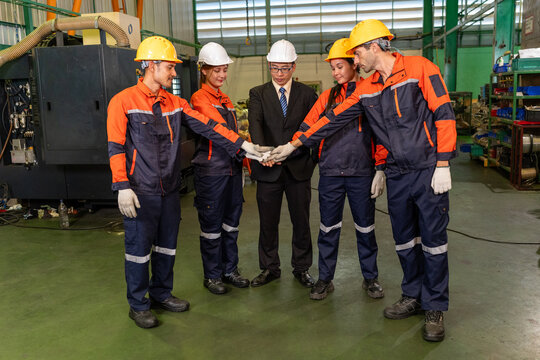 Engineer factory worker team hard hat uniform teamwork industry group wearing safety gear join hand inside plant