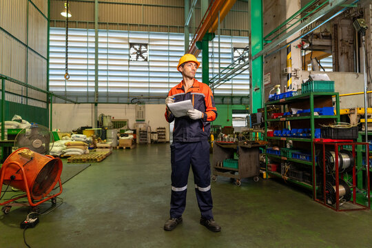 Engineer factory worker safety helmet industrial uniform clipboard, machinery workshop floor with shelf and tool storage