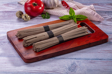 Fototapeta premium Soba noodles on wooden board with fresh ingredients