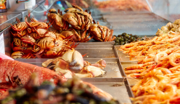 Fresh seafood display at a fish market stall featuring crabs, shrimp, and various shellfish in a vibrant setting