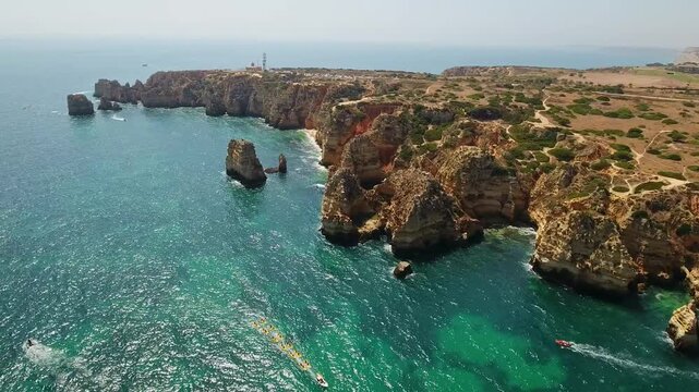 Majestic aerial view flying over the stunning rocky coastline of ponta da piedade in lagos, algarve, with its famous grottoes, sea stacks, and clear turquoise water of the atlantic ocean