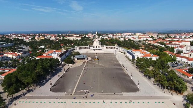 Dramatic aerial backward flight revealing the entire sanctuary of fatima, including the basilica of our lady of the rosary, the large esplanade, and the surrounding city on a sunny day